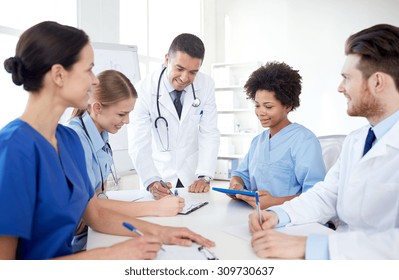 Medical Education, Health Care, People And Medicine Concept - Group Of Happy Doctors Or Interns With Mentor Meeting And Taking Notes At Hospital