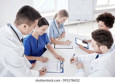 Medical Education, Health Care, People And Medicine Concept - Group Of Happy Doctors Or Interns With Mentor Meeting And Taking Notes At Hospital