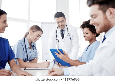 Medical Education, Health Care, People And Medicine Concept - Group Of Happy Doctors Or Interns With Mentor Meeting And Taking Notes At Hospital