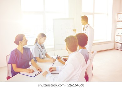 Medical Education, Health Care, Medical Education, People And Medicine Concept - Group Of Happy Doctors Or Interns With Mentor Meeting And Drawing On Flip Board At Hospital