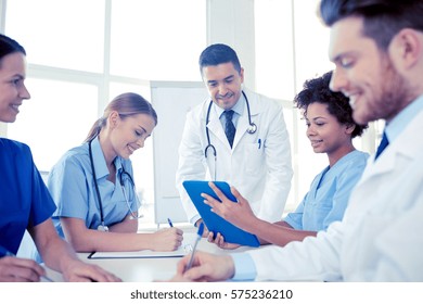 Medical Education, Health Care, People And Medicine Concept - Group Of Happy Doctors Or Interns With Mentor Meeting And Taking Notes At Hospital