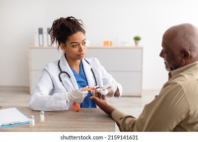 Medical Equipment For Help Concept. Portrait of black medical worker holding personal alarm button and giving it to male mature patient, sitting at table in office, explaining how to use alert - Shutterstock ID 2159141631