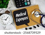 Medical Expenses text on speech bubble with alarm clock, magnifying glass and stethoscope on marble background