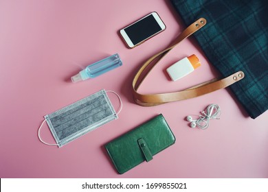 Medical face mask, alcohol spray bottle, alcohol-based hand sanitizer gel, tote bag, purse, smartphone, earphone on pink background. Essential items people need to survive in the COVID-19 epidemic. - Powered by Shutterstock