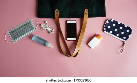 Medical face mask, alcohol spray bottle, alcohol-based hand sanitizer gel, tote bag, purse, smartphone, earphone on pink background. Essential items people need to survive in the COVID-19 epidemic. - Powered by Shutterstock