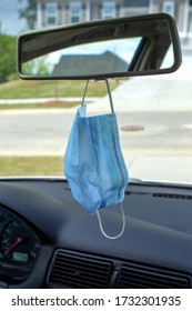 Medical Face Mask Hanging From A Review Mirror Inside Of A Car