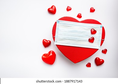 Medical face mask and red heart shaped gift box on white background. Healthcare and valentines day concept. Protection from coronavirus covid-2019