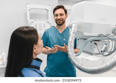 Medical facility's modern technology and x-ray machine. Patient seating at scanning table in modern clinic, listening doctor's explanation about X-ray examination and method of healthcare. - Powered by Shutterstock