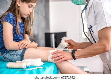 Medical female doctor bandaging young girl knee at the hospital - Powered by Shutterstock