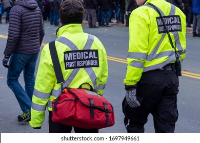Medical First Responders Walking Along A Road Wearing Black Wool Stocking Caps, Yellow Reflective Coats With Medical First Responder In Grey Letters Uniform.