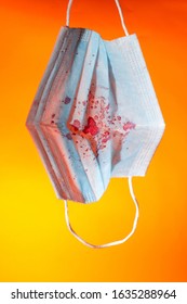 Medical Gauze Mask In Dried Blood Coronnavirus On An Orange Background. Close Up Copy Space