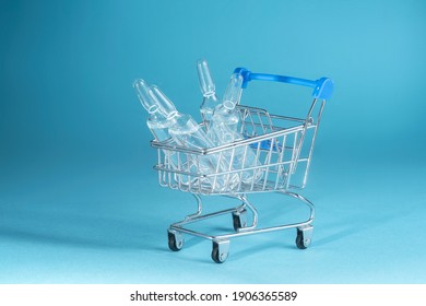 Medical Glass Ampoules In A Trolley On A Blue Background. Drugs And Vaccines Procurement Concept. Procurement Of Medicines And Copy Space