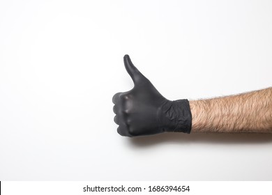 Medical Glove In Black On A White Background. A Hand Showing The Sign Of Ce Well Or Cool.