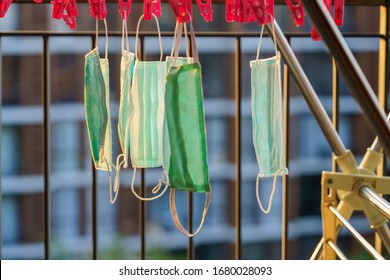 Medical Green Face Masks Are Hanging Out To Dry Using Pegged Clothesline On A Balcony In Asia For Reuse Because Of Limited Availability. Selective Focus.