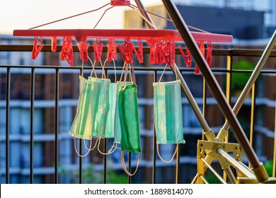 Medical Green Face Masks Are Hanging Out To Dry Using Pegged Clothesline On A Balcony In Asia For Reuse Because Of Limited Availability. Selective Focus.