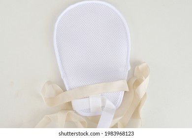 A medical hand restraint mitten showing the net meshing with straps to secure onto wearer's hand to restrict movement and prevent patient from scratching or removing IV and feeding tubes. - Shutterstock ID 1983968123