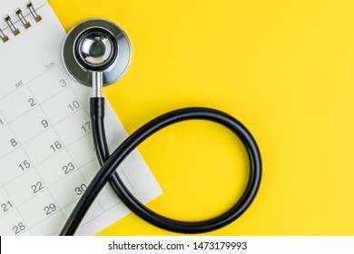Medical and health care calendar, reminder, schedule or appointment concept, doctor's stethoscope on white clean calendar with date on solid yellow background with copy space.