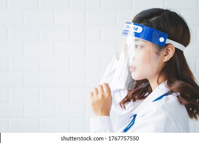 Medical Healthcare Beautiful Asian Doctor Wearing Face Shield Mask Protection From Infectious Disease Virus Bacteria Germs Coronavirus Covid-19, Safety Protection Working In Hospital Modern Office 