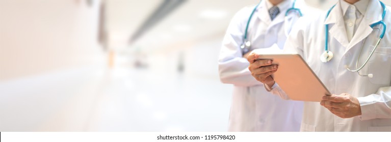 Medical Healthcare Doctor Team Concept. Physicians In White Gown And Stethoscope, Hand Holding Computer Tablet On Blur Background Corridor Hospital For Copy Space.