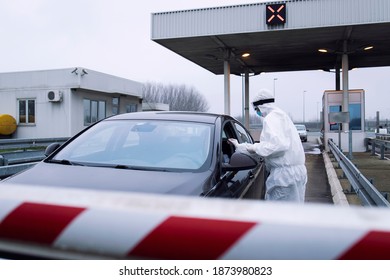 Medical Heath Care Worker In Protective White Suit Performing Nasal Swab Test For Corona Virus At Border Crossing.