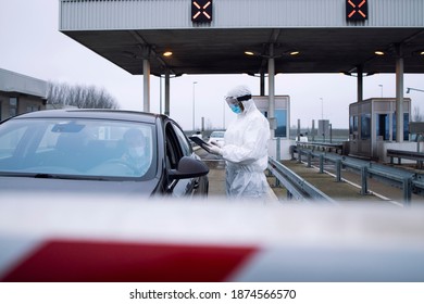 Medical Heath Care Worker In Protective White Suit Controlling Passengers And PCR Test At Border Crossing Due To Global Corona Virus Pandemic.