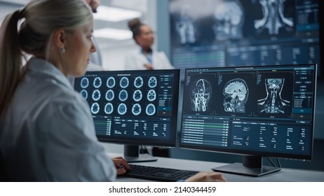 Medical Hospital Health Care Lab: Camera Captures Professional Neuroscientists Analysing CT Scan Finding Cure for Sick Patient and Female Neurologists Using Computer with Brain Scan MRI Images - Shutterstock ID 2140344459