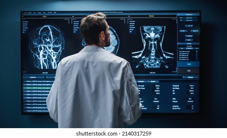 Medical Hospital Research Lab: White Male Neuroscientist Looking At TV Screen, Analyzing Brain Scan MRI Images, Finding Treatment For Patient. Health Care Neurologist Curing People. Back View Zoom