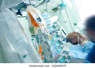 Medical Infusion Media On The Background Of The Patient And The Health Worker In A Hospital Ward Full Of Equipment.