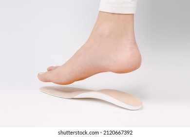 Medical insoles. Isolated orthopedic insoles on a white background. Foot care. Insole cutaway layers. Leg hanging over the insole. Treatment and prevention of flat feet and foot diseases.