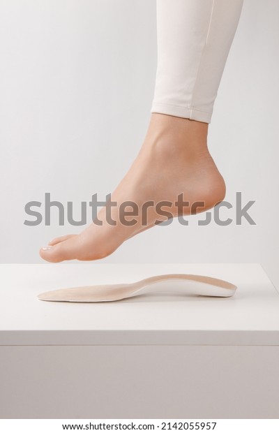 Medical insoles. Isolated orthopedic insoles on a\
white background. Treatment and prevention of flat feet and foot\
diseases. Foot care. Insole cutaway layers. Leg hanging over the\
insole.
