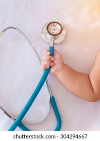 Medical Instruments Stethoscope In Hand Of Newborn Baby Girl.