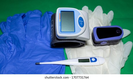 Medical Kit: Digital Body Thermometer, Pulse Oximeter And Arm Blood Pressure Monitor. Disposable Medical Gloves. Kit To Check Values During Coronavirus Covid 19. Green Background