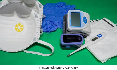 Medical Kit: Digital Body Thermometer, Pulse Oximeter, Medical Mask And Arm Blood Pressure Monitor. Disposable Medical Gloves. Kit To Check Values During Coronavirus Covid 19. Green Background