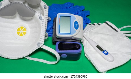 Medical Kit: Digital Body Thermometer, Pulse Oximeter, Medical Mask And Arm Blood Pressure Monitor. Disposable Medical Gloves. Kit To Check Values During Coronavirus Covid 19. Green Background