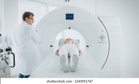 In Medical Laboratory Male Radiologist Controls MRI Or CT Or PET Scan With Female Patient Undergoing Procedure. Doctor Conducts Emergency Scanning With Advanced Medical Technologies.