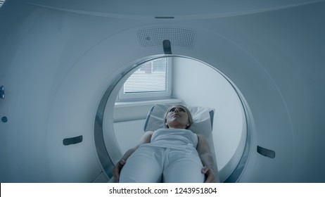 In Medical Laboratory  MRI Or CT Or PET Scan With Female Patient Undergoing Procedure. Doctor Conducts Emergency Scanning With Advanced Medical Technologies. In Blue Tone.