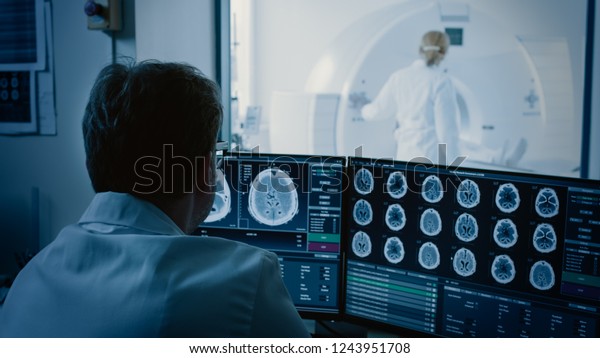 In\
Medical Laboratory Patient Undergoes MRI or CT Scan Process under\
Supervision of Radiologist, in Control Room Doctor Watches\
Procedure and Monitors with Brain Scans\
Results.