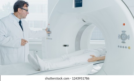 In Medical Laboratory Radiologist Controls MRI Or CT Or PET Scan With Female Patient Undergoing Procedure. High-Tech Modern Medical Equipment. Friendly Doctor Chats With Patient.