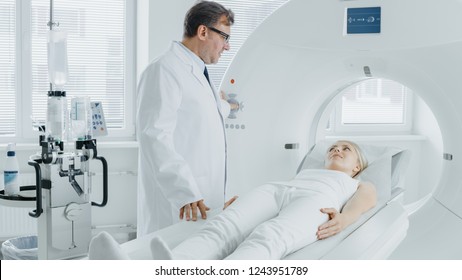 In Medical Laboratory Radiologist Controls MRI Or CT Or PET Scan With Female Patient Undergoing Procedure. High-Tech Modern Medical Equipment. Friendly Doctor Chats With Patient.