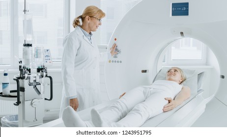 In Medical Laboratory Radiologist Controls MRI Or CT Or PET Scan With Female Patient Undergoing Procedure. High-Tech Modern Medical Equipment. Friendly Doctor Chats With Patient.