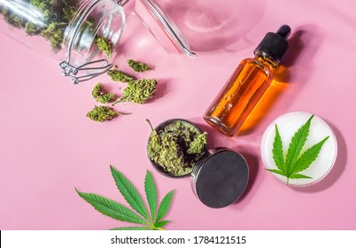 Medical Marijuana Buds CBD Oil And Grinder On Isolated On Pink, Medical Cannabis Concept