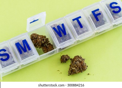 Medical Marijuana Buds In Daily Pill Organizer Sitting On Green Background