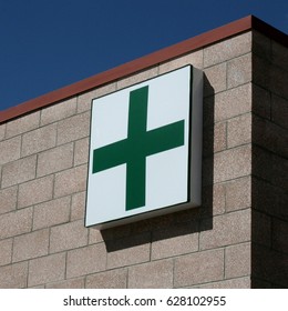 Medical marijuana generic green cross storefront sign on outside of pharmacy dispensary with blue sky in background