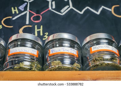 Medical marijuana jars against board with THC formula - cannabis dispensary background