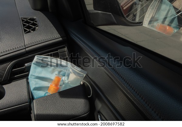 Medical mask, alcohol sanitizer hand gel and
hand sanitizer spray placed on console storage inside the car,
preparation of portable disinfectant alcohol spray, prevention of
Covid-19 concept.