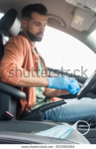 Medical\
mask in car near blurred driver in latex\
gloves