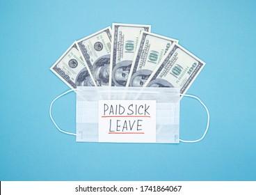 Medical Mask With Dollars And The Words Paid Sick Leave On A Blue Background. Concept Of Economic Dependence On The COVID-19 Coronavirus Pandemic