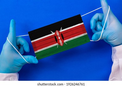 Medical Mask With The Flag Of Kenya In The Hands Of A Doctor, Flat Lay. Coronavirus Infection COVID-19