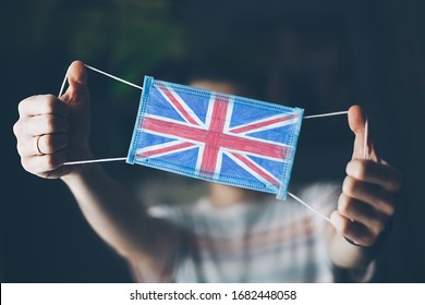 medical mask in hands of man, with the flag of  Great Britain painted. Copy space