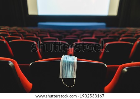 A medical mask hangs on a chair in an empty cinema hall. Pandemic and crisis in the industry. Delayed movie premieres